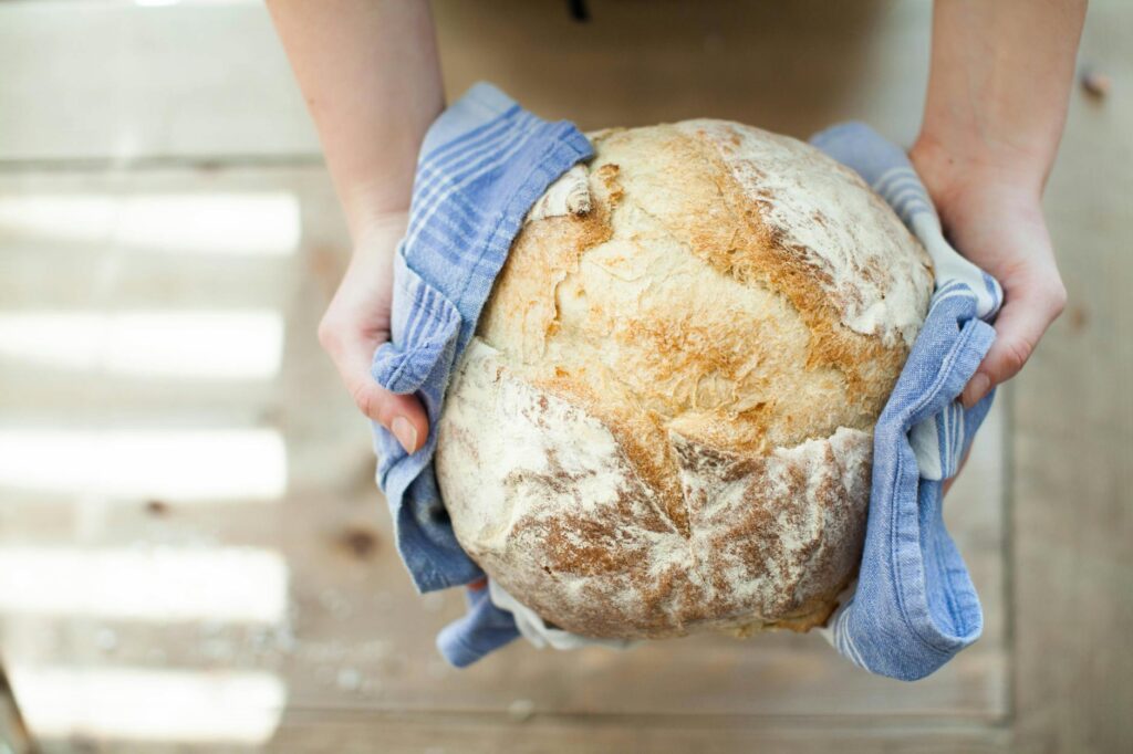 person holding baked pastry covered with towel